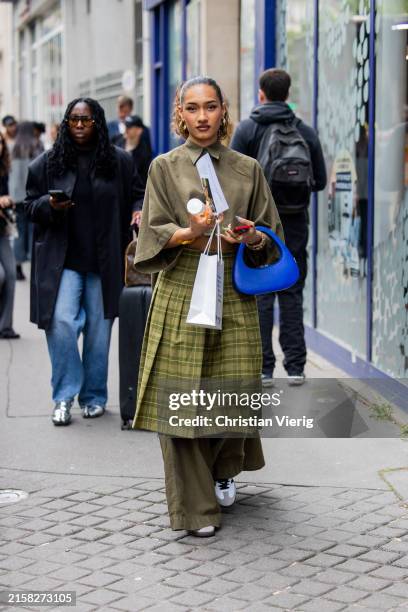 Guest is seen wearing blue bag, checkered skirt, pants, jacket outside Bianca Saunders during the Menswear Spring/Summer 2025 as part of Paris...