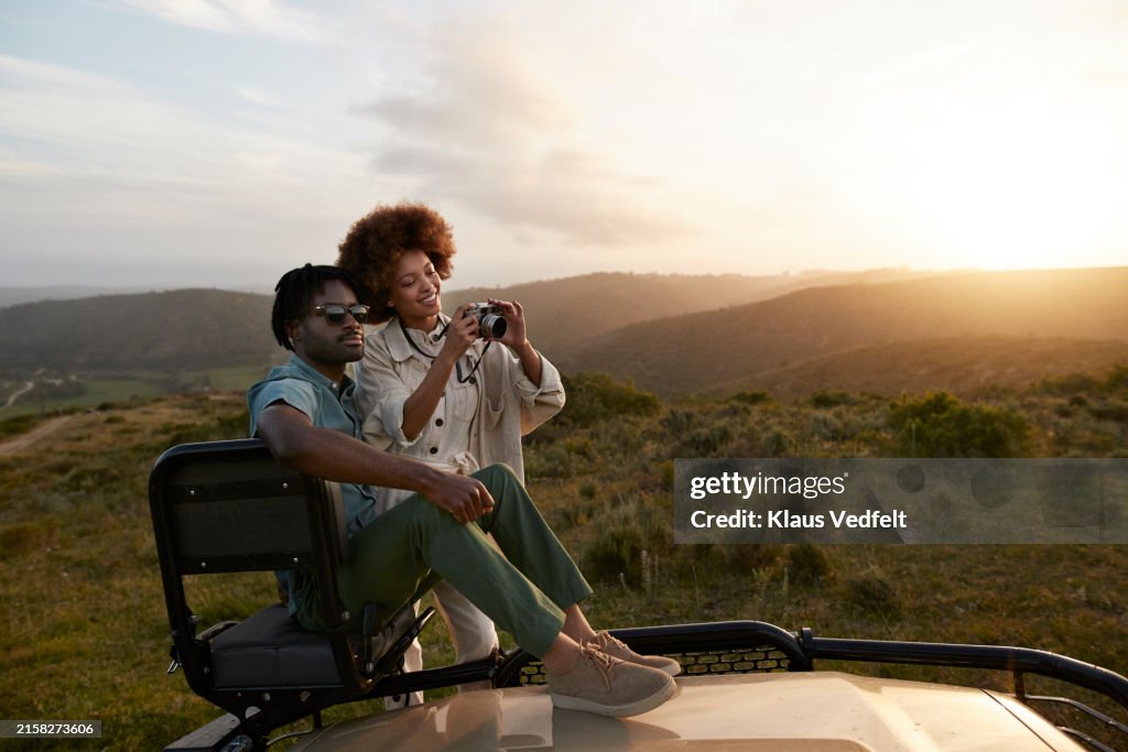 Smiling woman photographing through camera with boyfriend