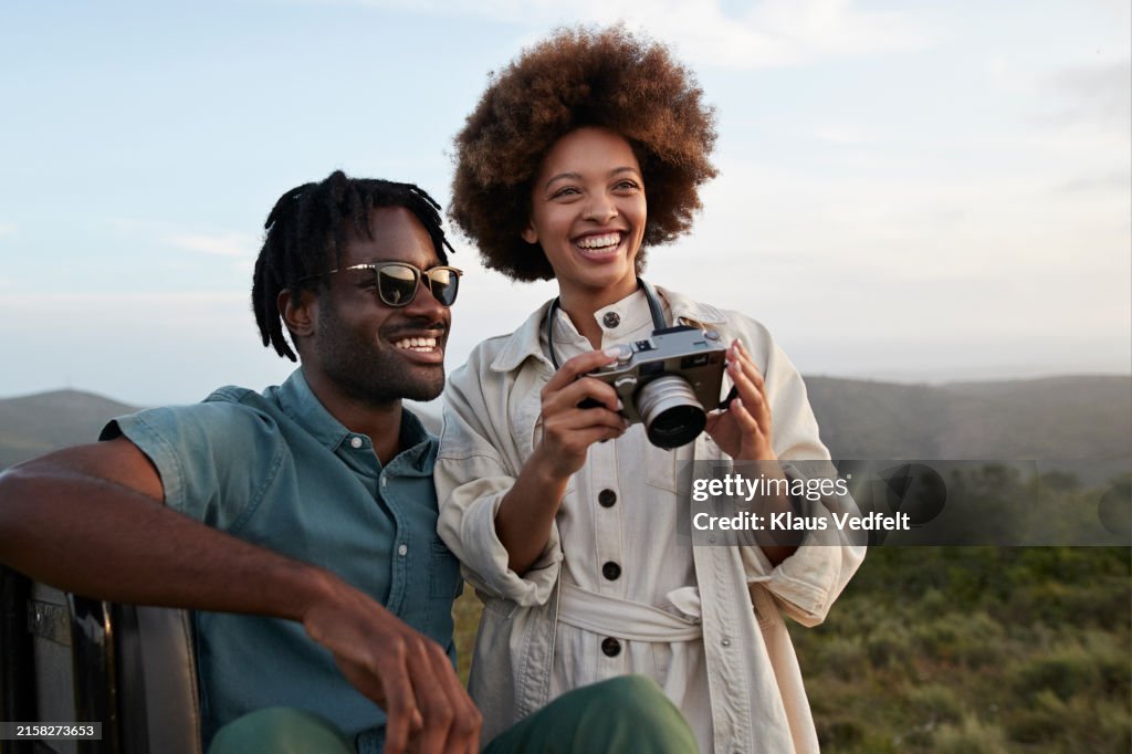 Happy young couple with camera in national wildlife park