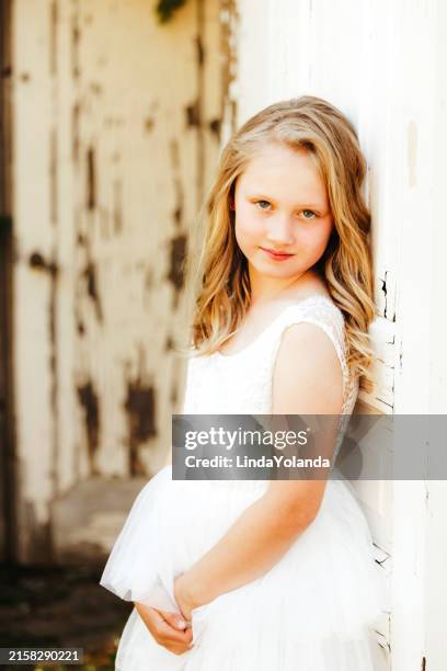bambina che si appoggia alla porta rustica - vestito bianco foto e immagini stock
