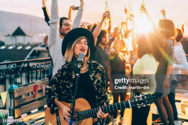 friends enjoying a guitar performance on the rooftop - acoustic guitar stock pictures, royalty-free photos & images