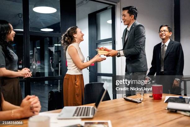 manager giving welcome gift to a visiting international team member in meeting toom - receiving stock pictures, royalty-free photos & images