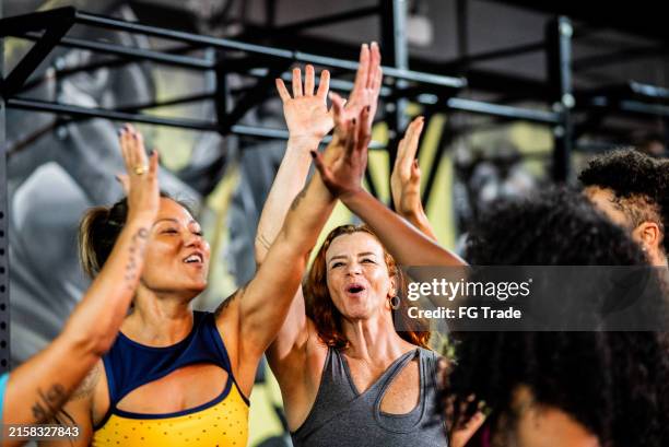 amigos celebrando tomados de la mano en el gimnasio - centro de bienestar fotografías e imágenes de stock
