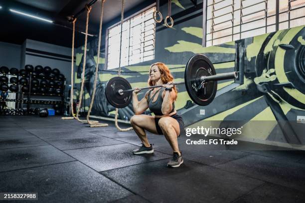 mature woman doing weightlifting in the gym - crouching stock pictures, royalty-free photos & images