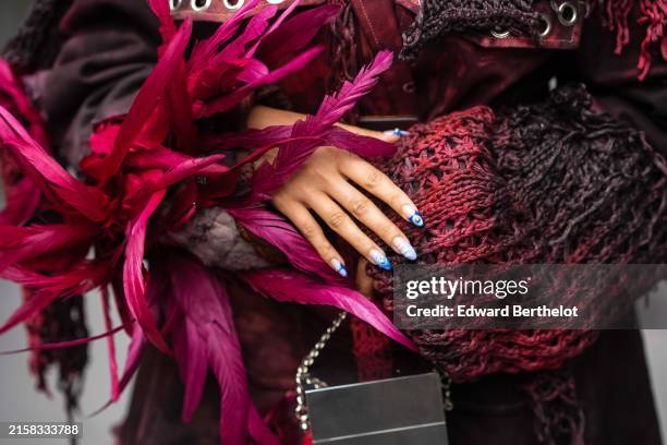 Samia Laaboudi wears a washed light and dark red dress/pattern with studded holes black with faded red knit and red and pink long feather coming out...
