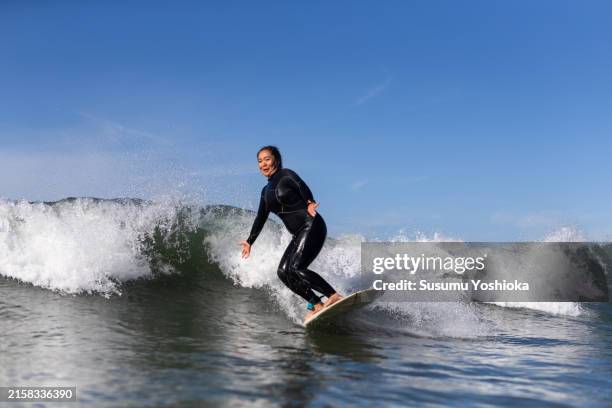 surfers enjoy surfing while on a surf trip. - wetsuit stock pictures, royalty-free photos & images