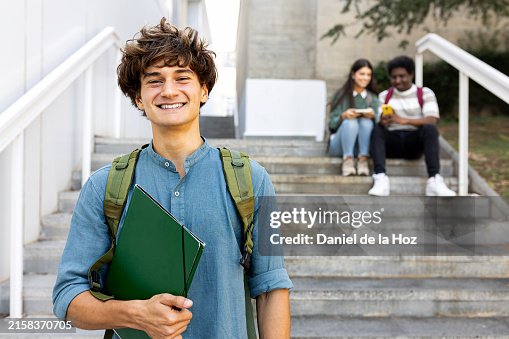 Happy smiling male teen college student on campus holding books looking at camera. Copy space. Happy smiling male teen college student on campus holding books looking at camera. Copy space.
