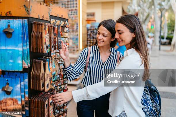 zwei freundinnen kaufen souvenirs auf dem straßenmarkt in palma de mallorca in spanien - souvenir stock-fotos und bilder