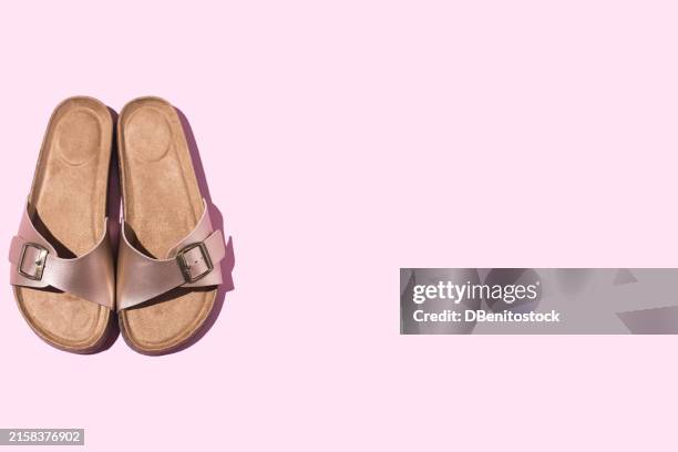 a pair of metallic cork pink sandals with metal buckles with a cork sole, on the left side, on a pink background. metallic sandals concept, gold buckles, cushioned, summer, minimalist, casual style - strap stock pictures, royalty-free photos & images