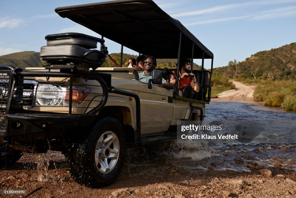Smiling tourists in off-road safari vehicle crossing river