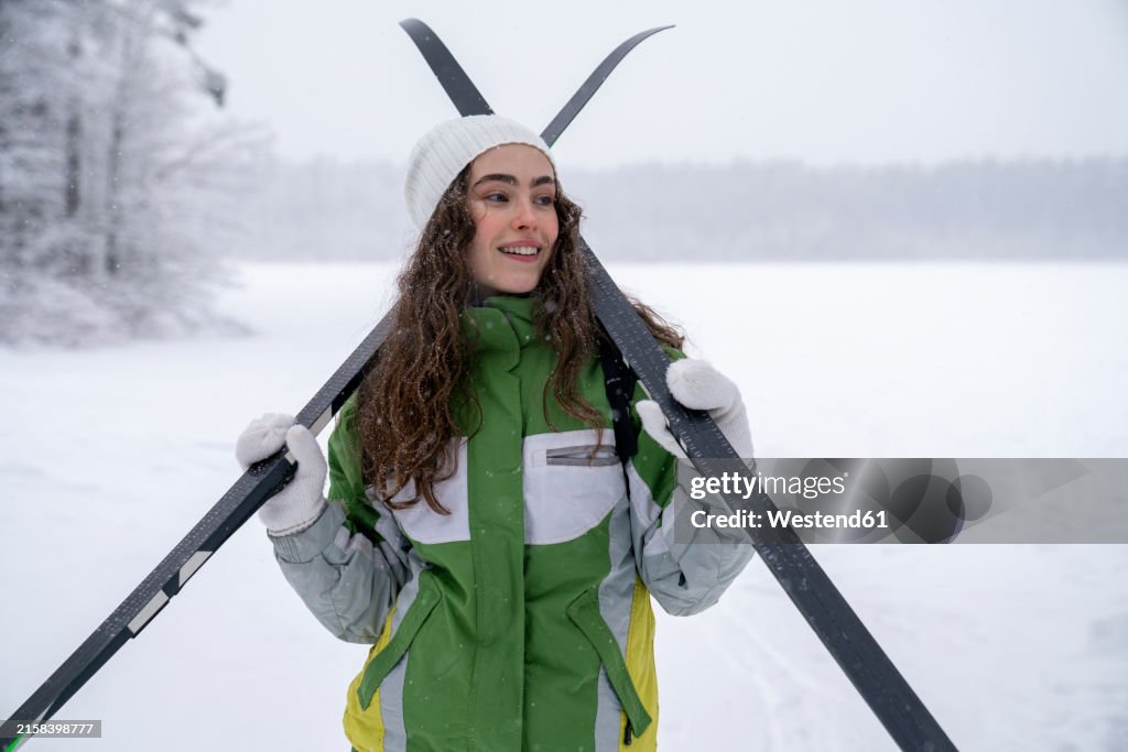 Skier carrying skis in snow forest
