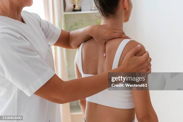 physiotherapist treating patient for chiropractic adjustment of back in hospital - osteopathie stockfoto's en -beelden