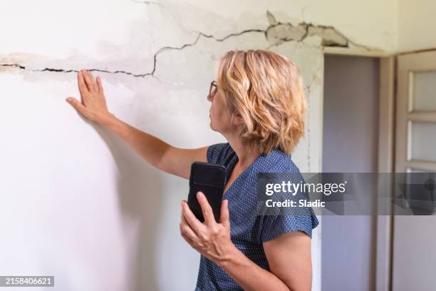 mujer mirando una pared dañada - terremoto fotografías e imágenes de stock