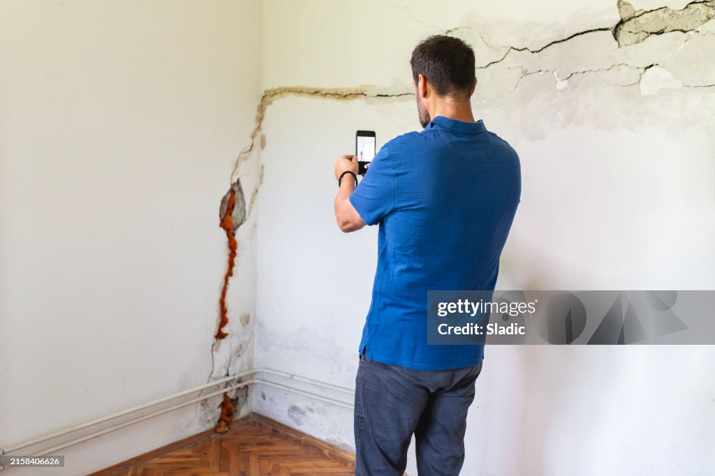Reifer Mann schaut auf eine beschädigte Wand