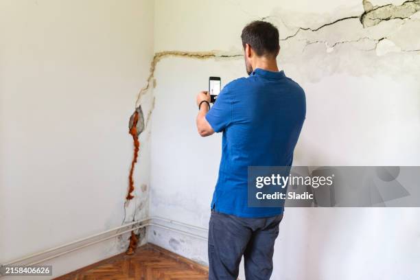mature man looking at a damaged wall - damaged stock pictures, royalty-free photos & images