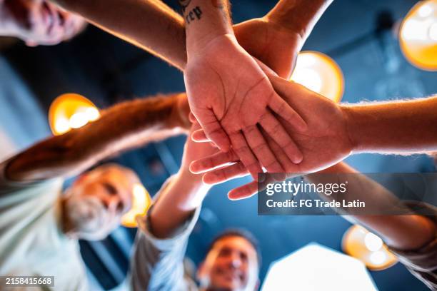 primo piano di uomini che impilano le mani durante la terapia di gruppo maschile - servizio sociale foto e immagini stock