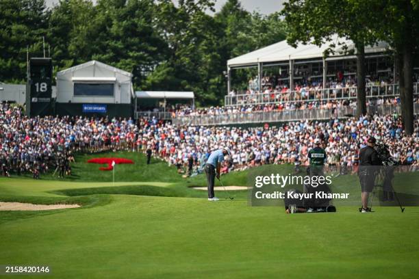 Fans watch from the 18th hole green as Scottie Scheffler prepares to play his approach shot during the final round of the Travelers Championship at...