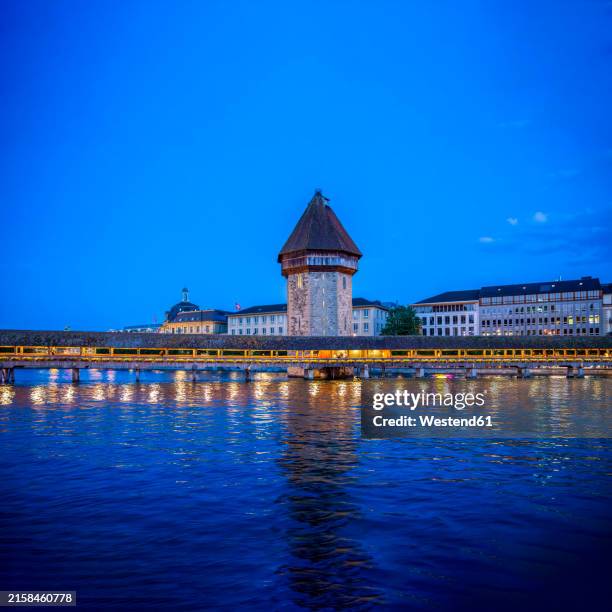 illuminated chapel bridge at blue hour in lucerne - kapellbrücke stock-fotos und bilder
