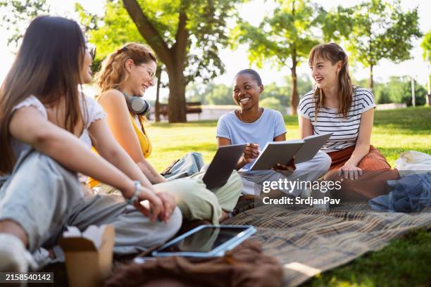 estudiantes universitarias modernas y multirraciales estudiando juntas en el parque del campus - edificio público fotografías e imágenes de stock