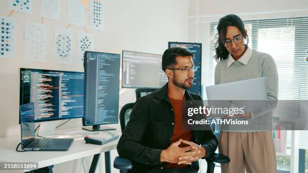 programmatori ispanici che rivedono il codice sul laptop nell'ufficio moderno - programmatore di computer foto e immagini stock