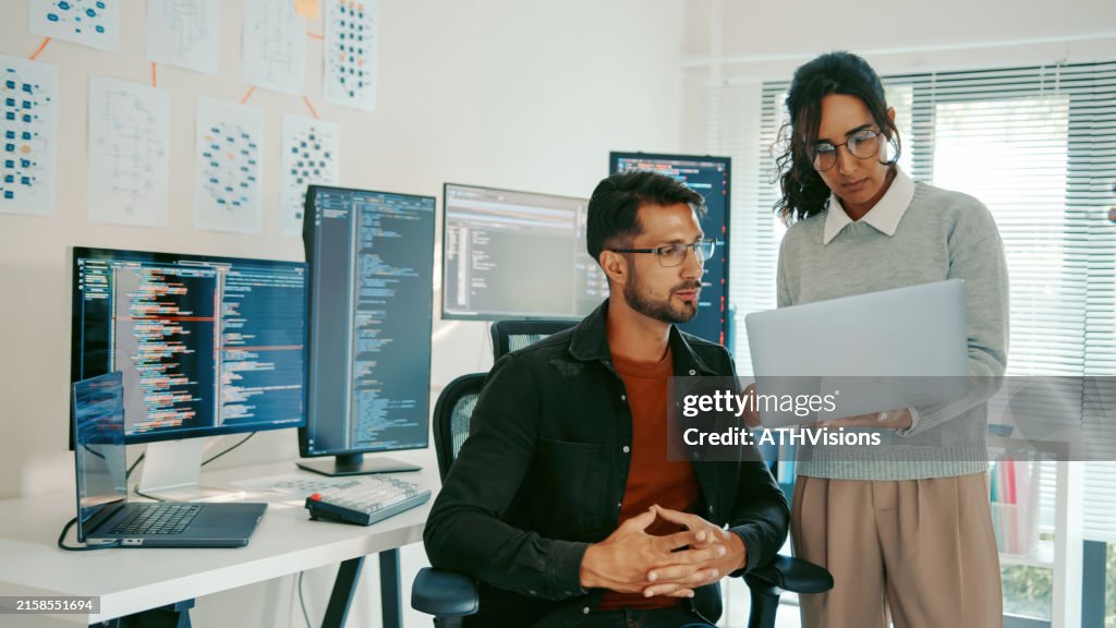 Hispanic Programmers Reviewing Code on Laptop in Modern Office