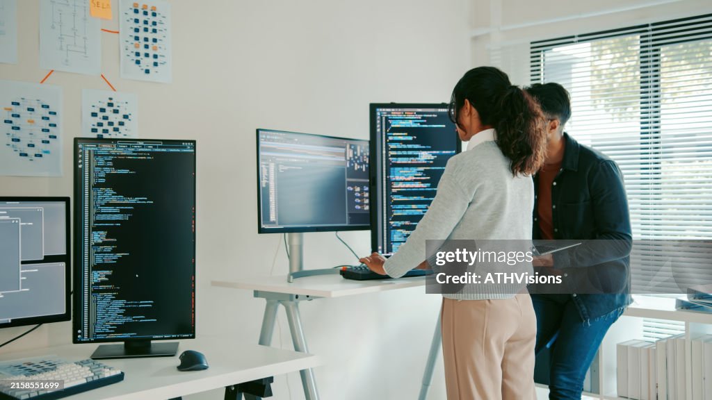 Hispanic Programmers Reviewing Code on Laptop in Modern Office