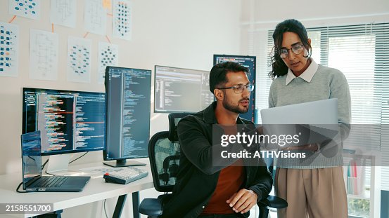 Two Hispanic programmers reviewing code on a laptop in a modern office Two Hispanic programmers reviewing code on a laptop in a modern office