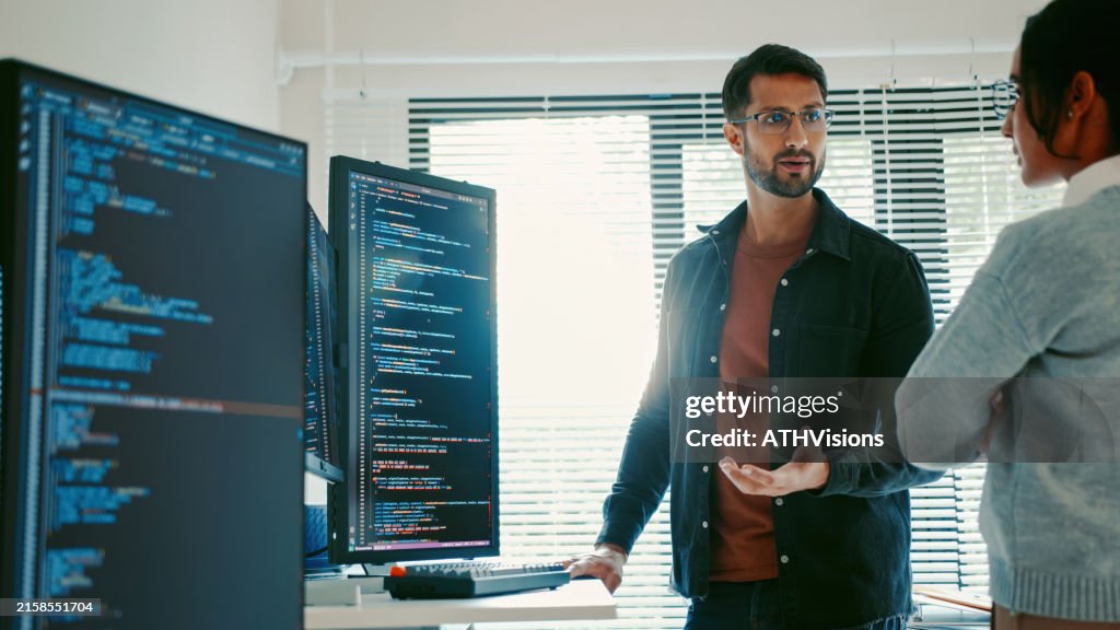 Programmatori Latinx collaborativi che discutono di codice su monitor, lavoro remoto e ibrido, intelligenza artificiale e apprendimento automatico