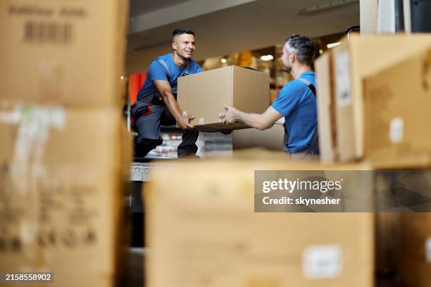 happy warehouse workers unloading boxes in storage room. - descarregar atividade imagens e fotografias de stock