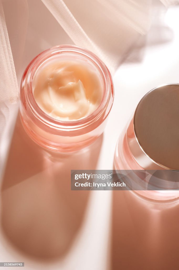 Texture of Cosmetic product in glass Jar - Skincare Face Cream, Refreshing Hydration Water Cream or Hand Cream and gorgeous flowy tutu tuile nylon skirt in natural pastel pink beige peach color Peach color.