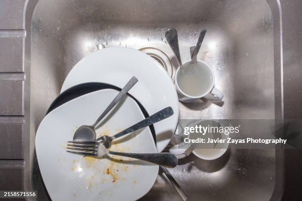 pile of unwashed dishes stacked in a kitchen sink - sink stock pictures, royalty-free photos & images