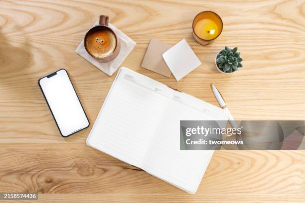 empty screen mobile phone and blank note book on coffee table top. - coffee table stock pictures, royalty-free photos & images