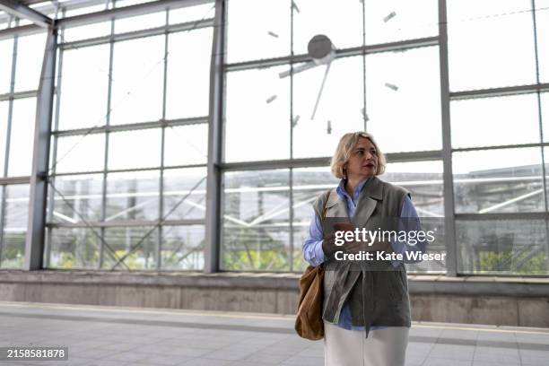 beautiful business woman using smart phone while waiting at ticket lobby in train station - flughafen wien stock-fotos und bilder