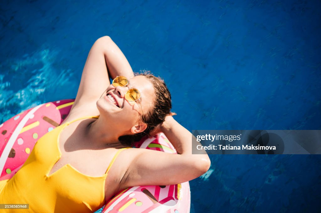 Beautiful woman is relaxing on the inflatable ring in the swimming pool. Summer vacation concept.