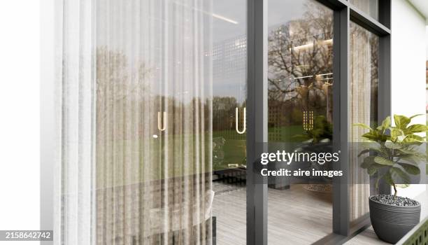 side view of the exterior of some glass doors of a bedroom in the foreground towards the patio - porta scorrevole foto e immagini stock