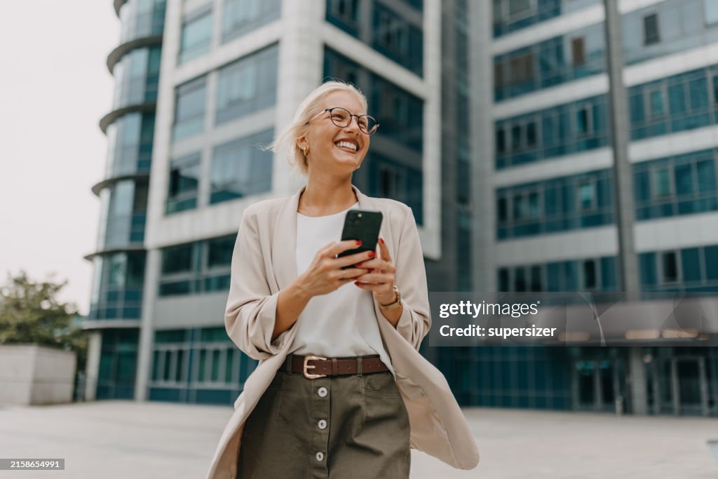 Business woman checking messages outdoors in cityscape.