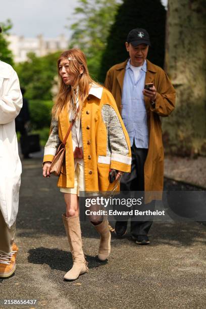 Guest wears a brown orange oversized coat with white and light gray pattern, white button up long sleeve shirt, pastel yellow shirts, brown suede bag...