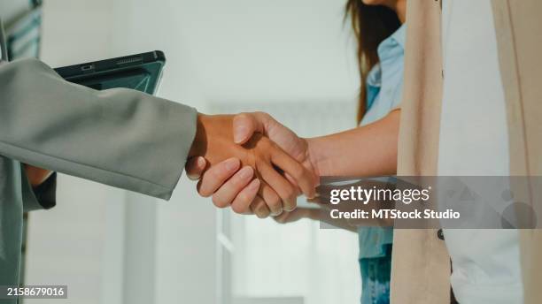 close-up of asian female real estate agent handshaking after complete agreement with tenants after showing new houses. landlord selling real estate to happy couple customer for investment. - landlord stock pictures, royalty-free photos & images