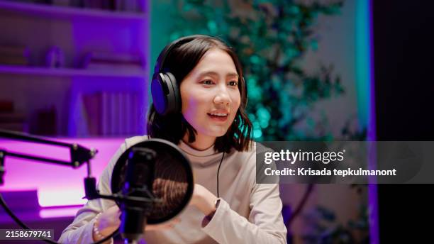 jeune femme asiatique ouvrant des aides visuelles tout en parlant au public lors d’une session de podcast. - interview photos et images de collection