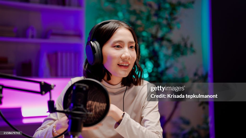 Young Asian woman opening visual aids while talking to audience during a podcast session.