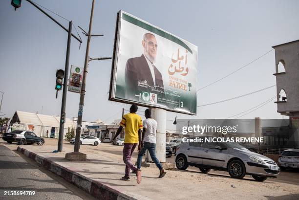 People walk past a billboard of Mauritanian Islamist candidate Hamadi Ould Sid' El Moctar, president of the National Rally for Reform and...