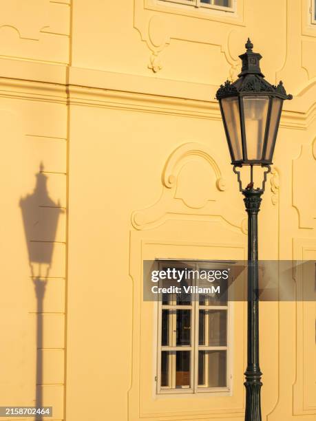 An ancient street lamp and its shadow on the facade.