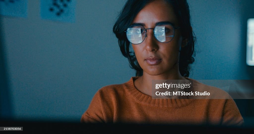 Female computer programmer works on complex software development tasks at her home office late into the night. Software developer, artificial intelligence and programming.