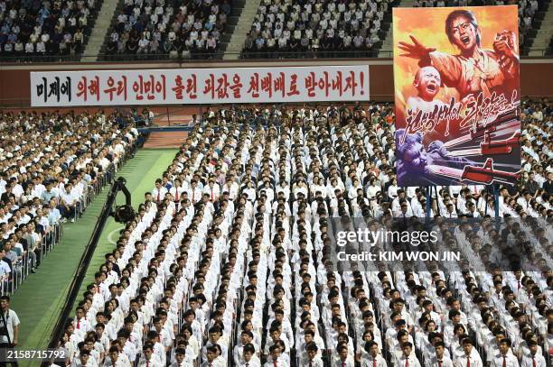 Banner reading "Let's get a hundred times the amount of blood shed by our people by the American Emperor" is displayed as participants take part in a...