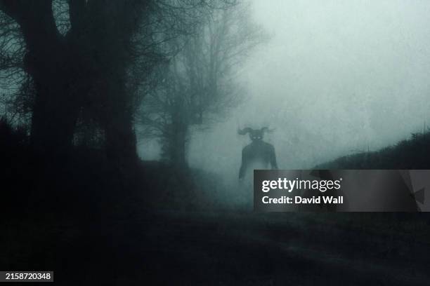 a supernatural demon. standing on a road. on a spooky foggy night in the countryside. with a grunge abstract edit. - aterrorizado imagens e fotografias de stock