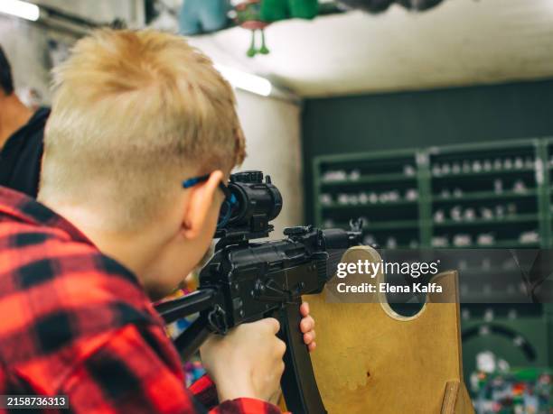 boy shoots from a gun at a shooting range - atirador imagens e fotografias de stock