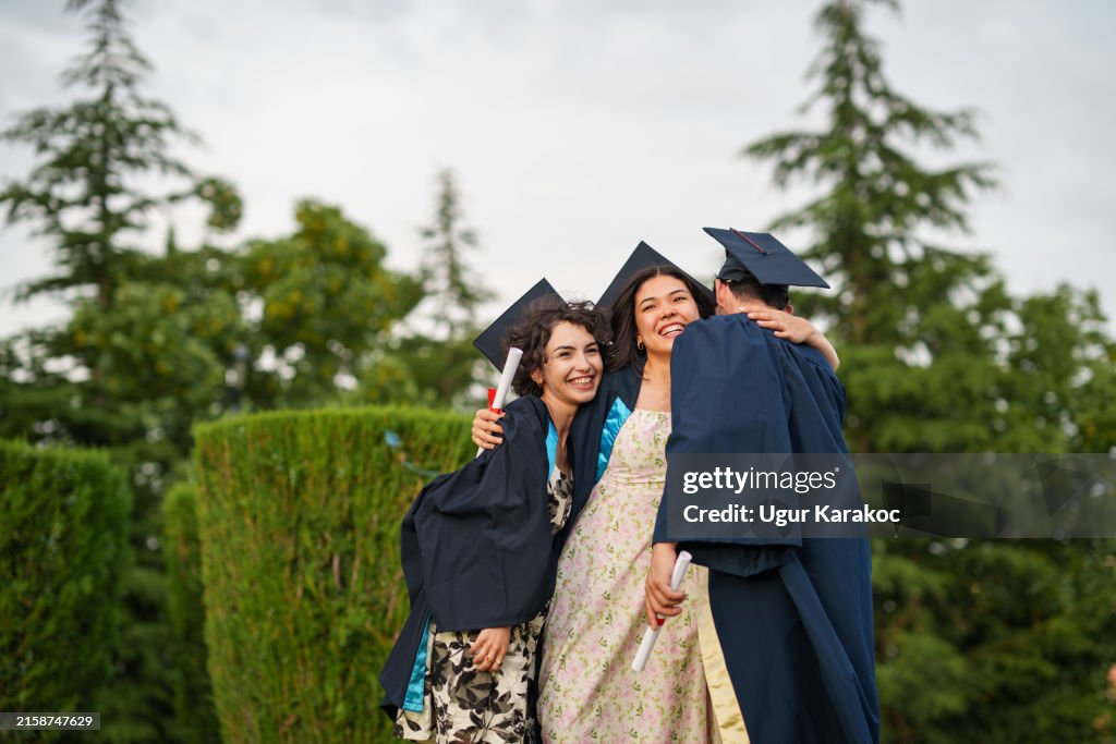 Graduating people hugging each other.