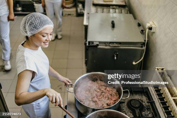 baker stirring meat filling in industrial kitchen - roer stockfoto's en -beelden