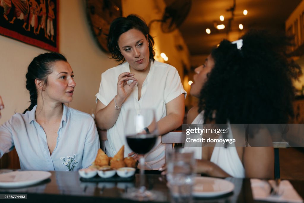 Indian Chef Serving Samosa to Young Women Seating in a Restaurant