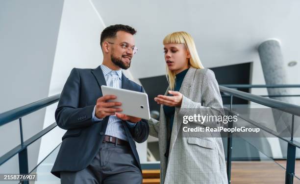 zwei kollegen diskutieren etwas auf einem tablet. - geschäftsprozess stock-fotos und bilder